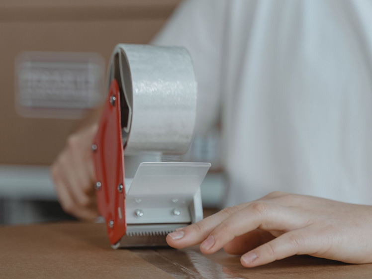 Sealing Cardboard Shipping Boxes with Packaging Tape Gun