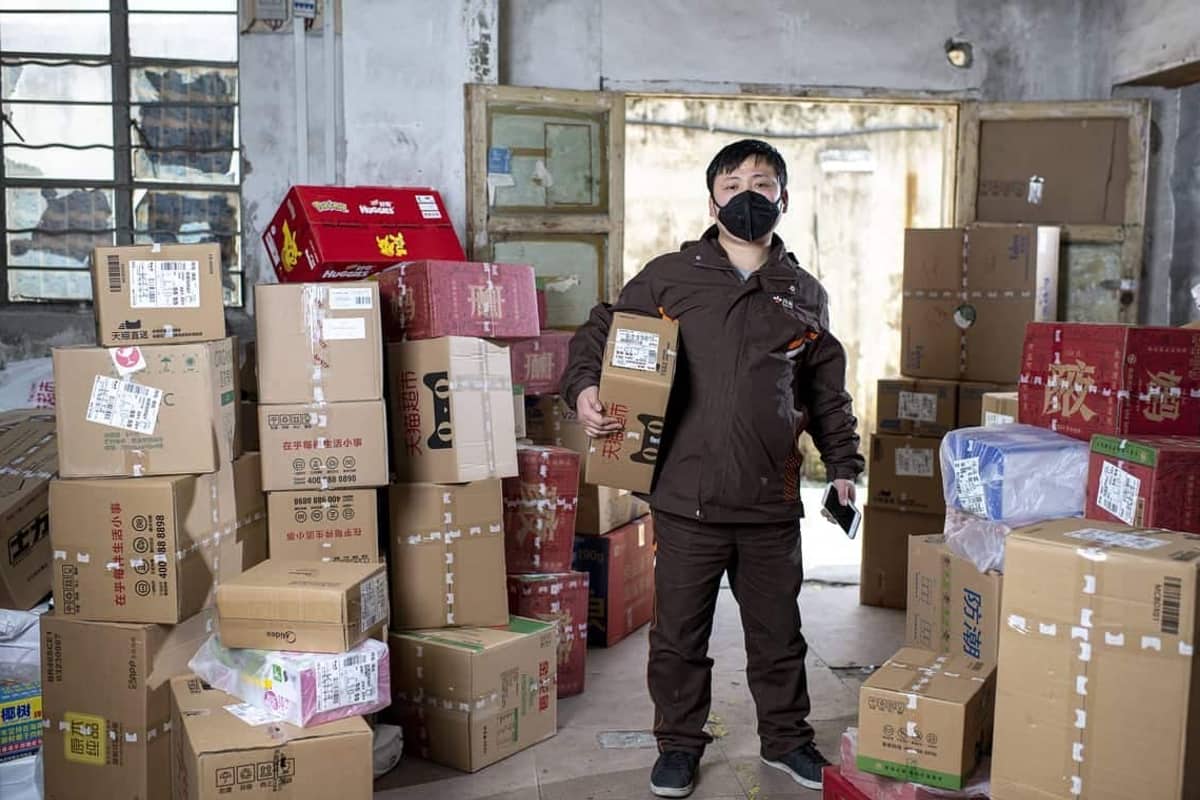 Parcel worker holding a package at a collection point in Wuhan