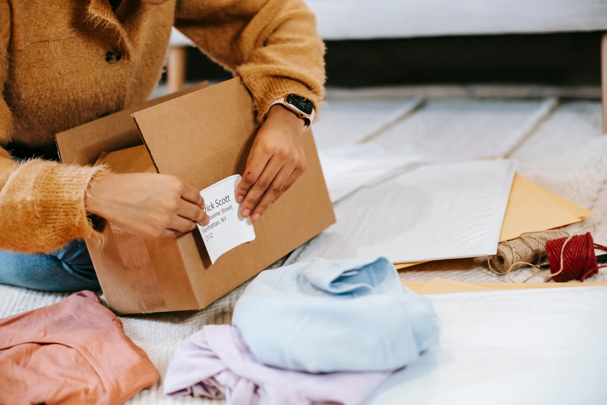 Hands attaching a shipping label to a packed carton
